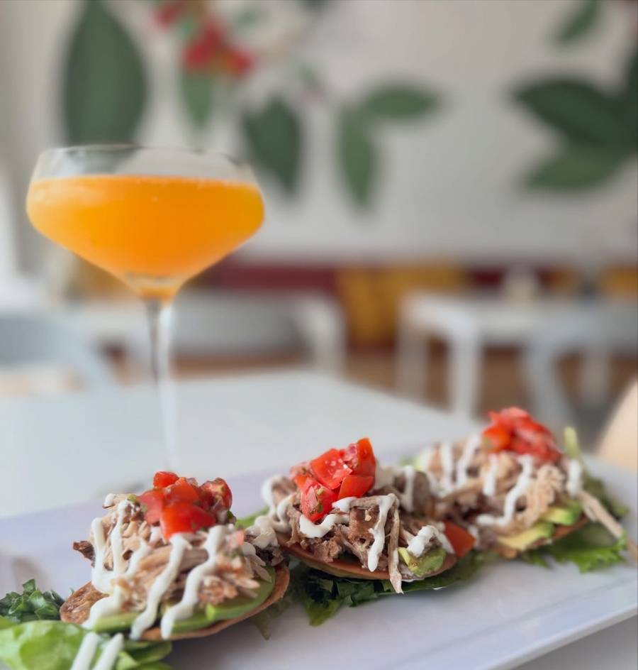 Three pulled-pork tostadas topped with pico de gallo and crema, next to a mimosa, at Aroma que Latte