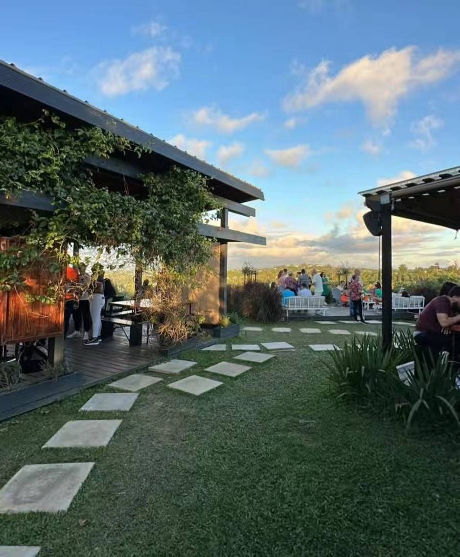 The garden and open-air deck at Asador San Miguel at golden hour, with guests at the tables and the mountains beyond