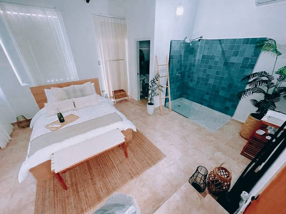 A bedroom with an open walk-in shower finished in turquoise tile