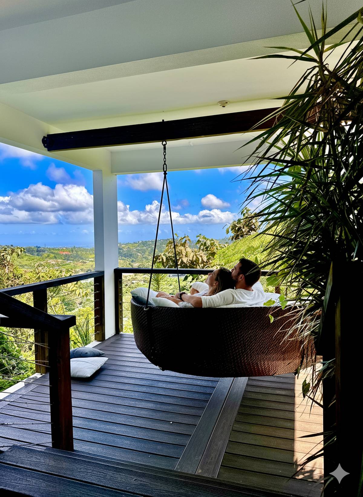 A couple lying on the round hanging swing bed on the deck, looking out over the mountains